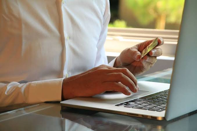 A man in a white shirt focused on his laptop
