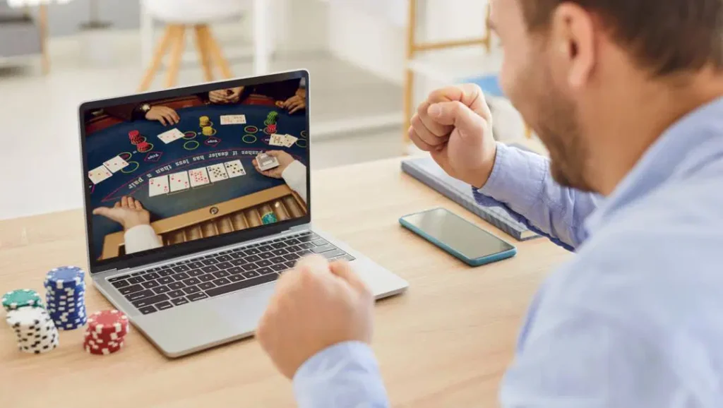 Man celebrating in front of laptop after winning in online casino games